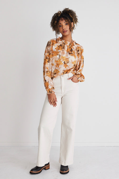model in orange floral top and white jeans