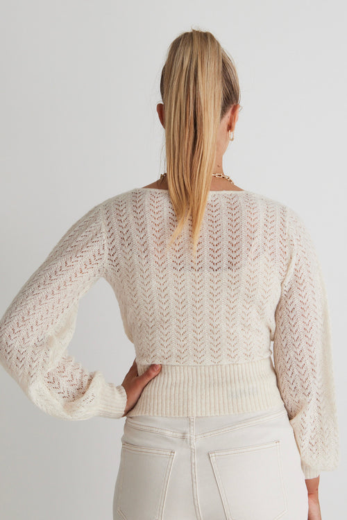 model posing in white knit long sleeve sweater