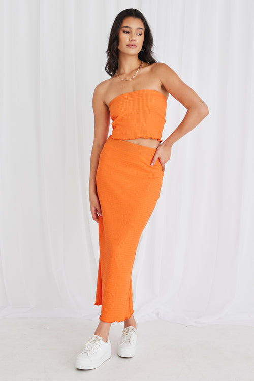 Model wearing orange bandeau top and maxi skirt set