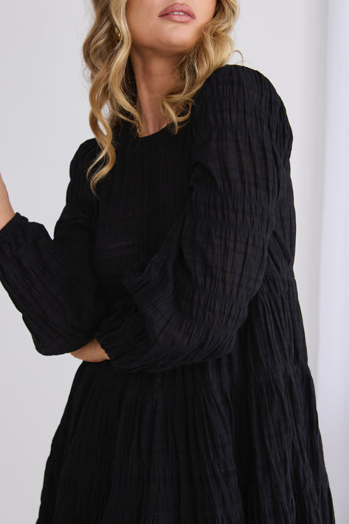 model wears a black mini dress