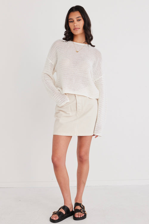 model in white knit crochet jumper and white mini skirt