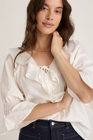 Model wears a white ruffle top