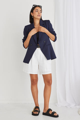 model in navy blazer and white shorts and black sandals