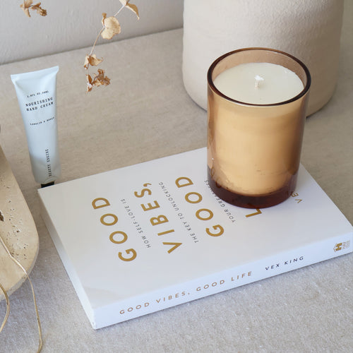 Candle, book, and decorative items on a surface with a neutral background