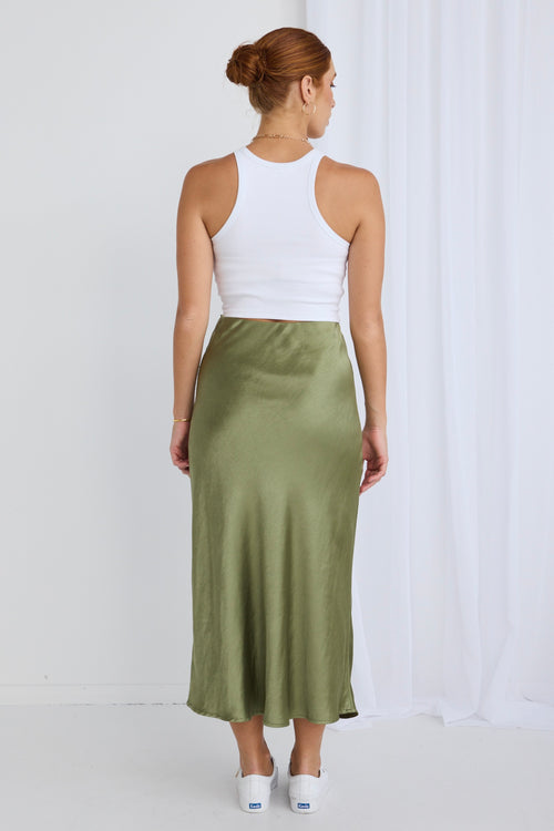 Model wears a green satin skirt with a white top and cardigan