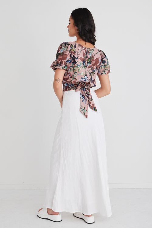 model wears a blush floral top with white maxi skirt