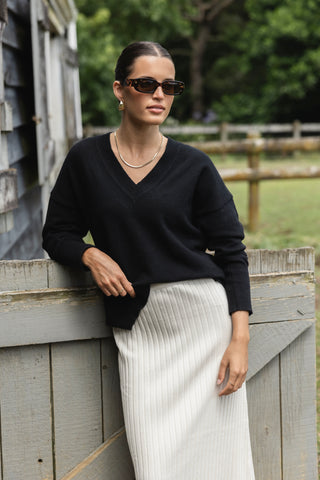 Model wears a black knit with cream knit skirt