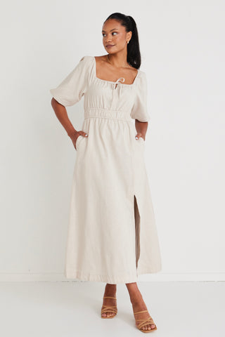 Model wears a linen  midi dress with a slit in the leg. 