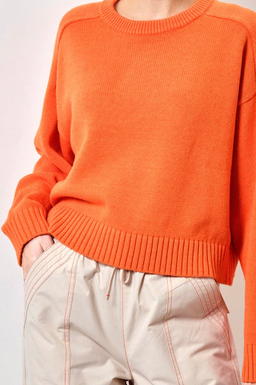 Model wears an orange knit 
