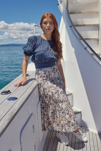 model wears a blue top with a floral maxi skirt