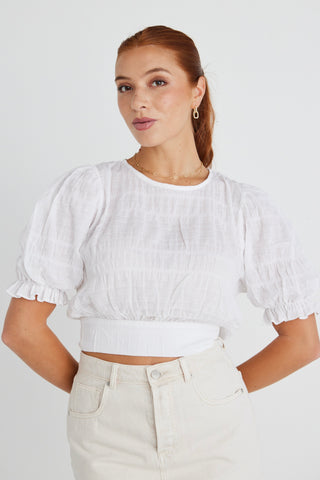 model wears a white shirred cotton top. 