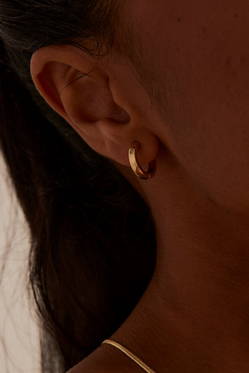 modeling wearing Simple Huggie Gold Earrings