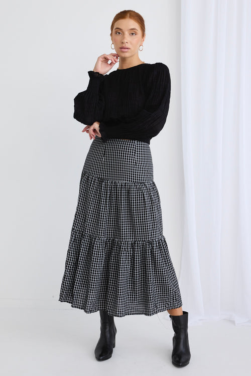 model wears a black check midi skirt