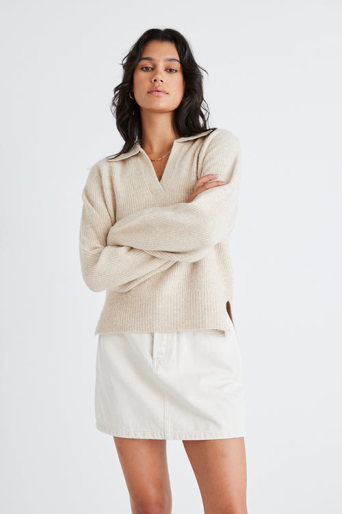 Model wears a beige chunky knit with a denim skirt