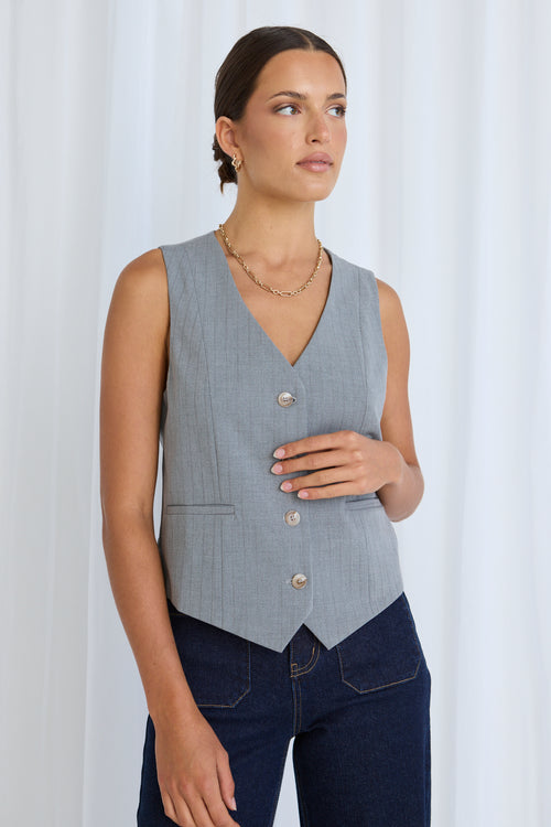 model wears a grey vest with jeans