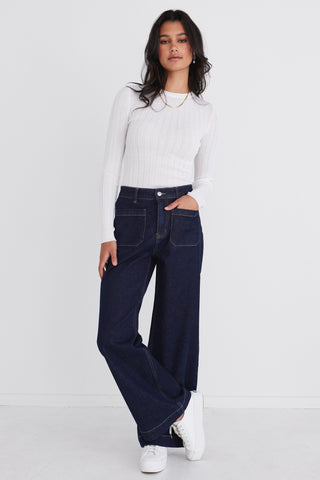 Model wears dark denim jean with white top 