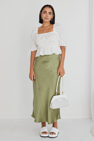 model wears white top and green satin maxi skirt