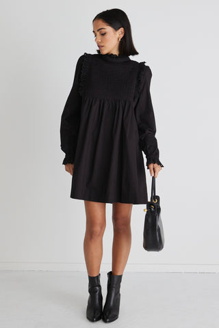model wears a black mini dress