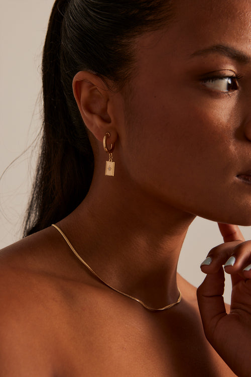 Model wears gold pendant earring 