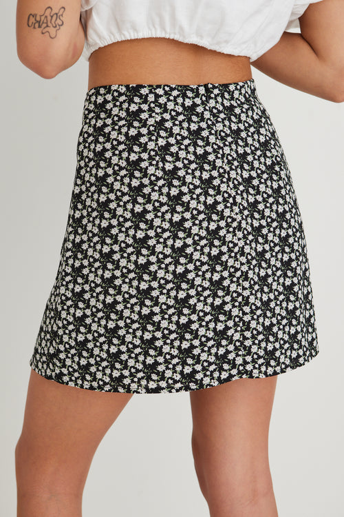 model wearing white top and black floral mini skirt