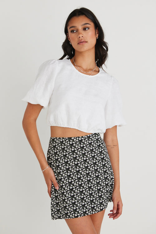 model wearing white top and black floral mini skirt
