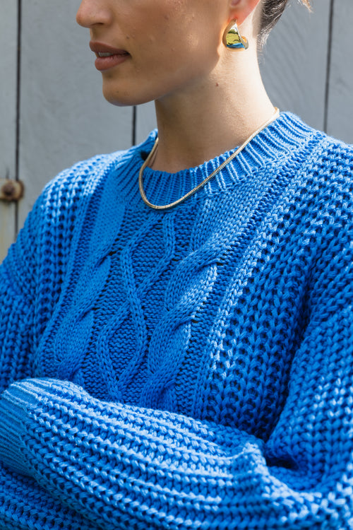 model wears a blue cable knit with black pants