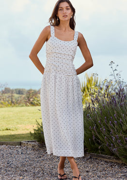 Woman in a white dress standing outdoors with lavender and greenery in the background