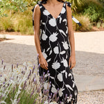 Woman in a black and white floral dress standing in a garden.