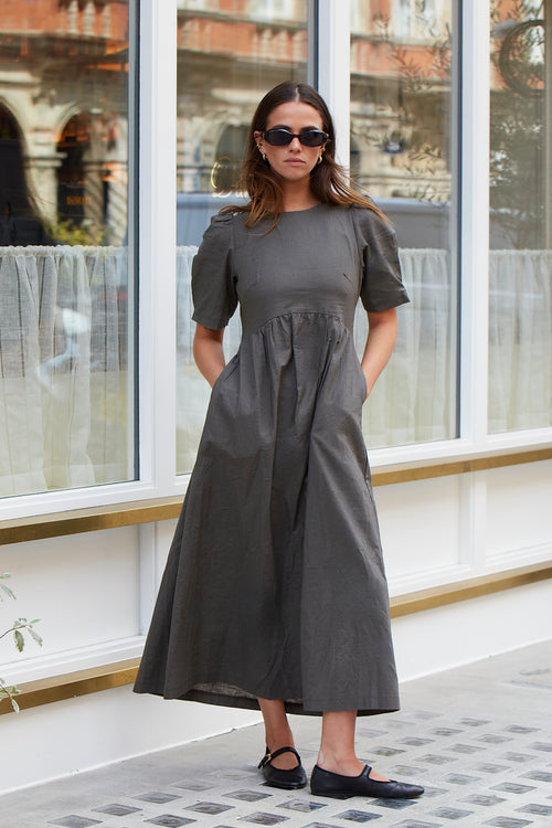 Model wears a khaki midi dress with rounded neckline