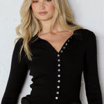 Woman wearing a black button-up shirt with a white background