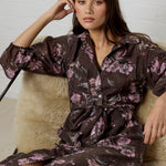 Woman wearing a dark floral dress sitting on a textured chair.