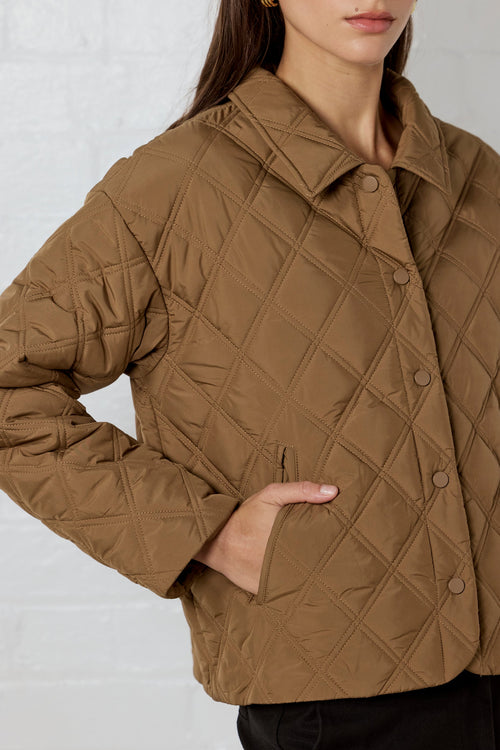 Brown quilted jacket worn by a person on a plain background