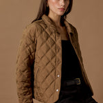 Woman wearing a quilted brown jacket against a brown background