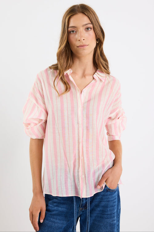 Woman wearing a pink and white striped shirt with rolled-up sleeves on a plain background
col_pattern