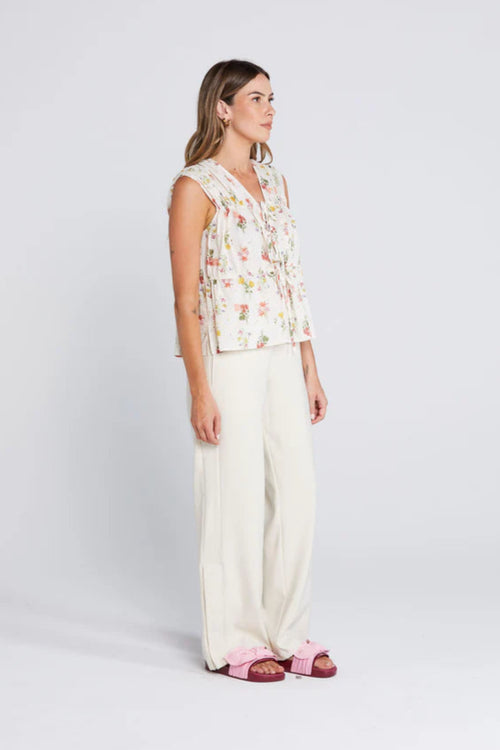 woman wearing a cream floral top and cream pants