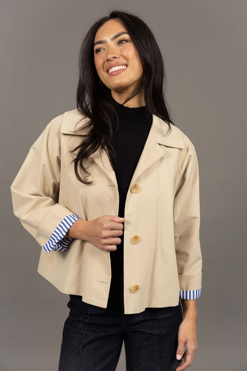 Woman wearing a beige jacket with a gray background