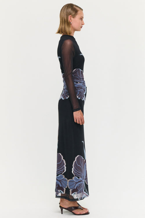 Woman wearing a black dress with blue floral patterns on a white background