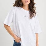 Woman wearing a white t-shirt and blue jeans on a plain background