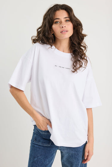 Woman wearing a white t-shirt and blue jeans on a plain background