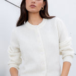 Woman wearing a white sweater against a light gray background