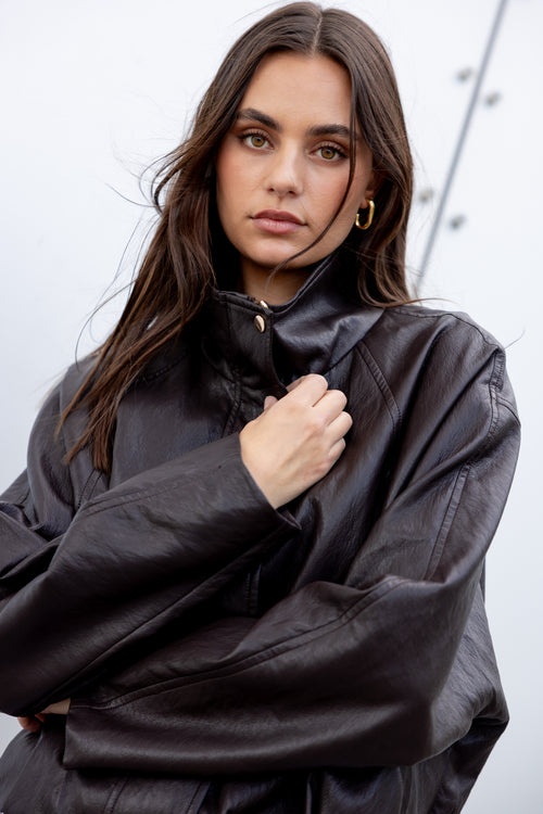 Woman wearing a black leather jacket against a light background