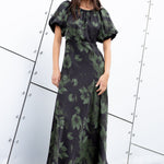Woman wearing a green floral dress against a modern architectural background