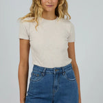 Woman wearing a white t-shirt and blue jeans against a plain background