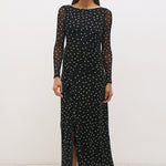 Woman wearing a black dress with white polka dots on a white background