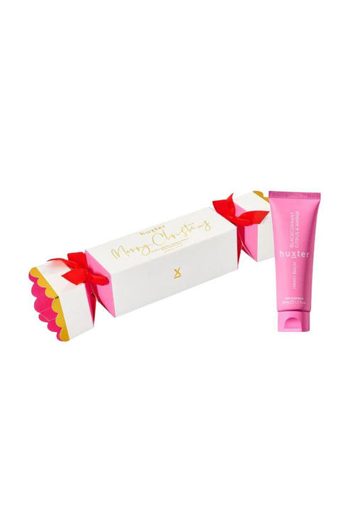 Pink tube of lip balm and white box with red bow on a white background