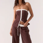 Woman wearing a brown and white strapless outfit on a white background