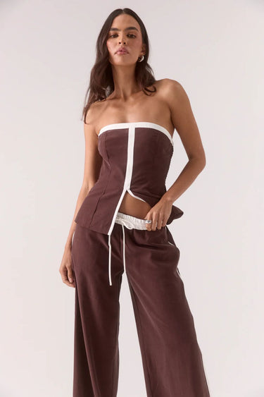 Woman wearing a brown and white strapless outfit on a white background