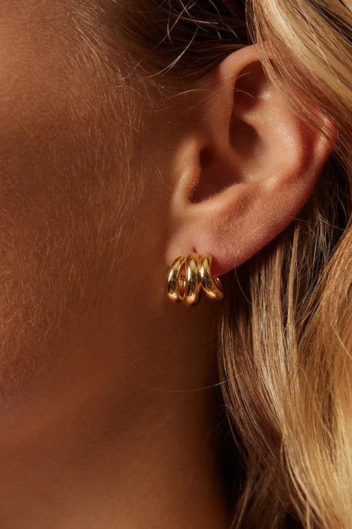 Close-up of a person wearing gold hoop earrings with soft focus on skin and hair.