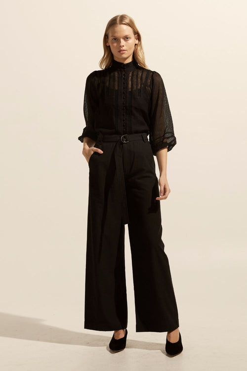 model wears a black blouse with black pants