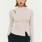 Woman wearing a beige long-sleeve top with a cutout design on a white background
